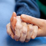 Personne âgée souriante assise près d’une fenêtre dans un EMS à Genève, symbolisant la tranquillité et le confort d’une résidence adaptée.